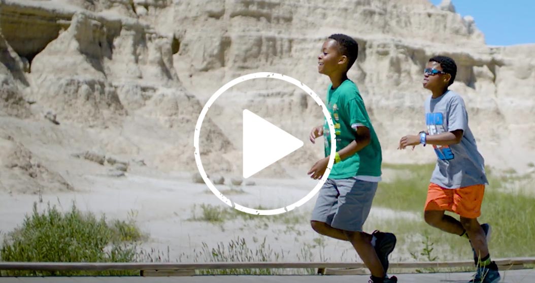 Two kids running with a YouTube play button overlay.