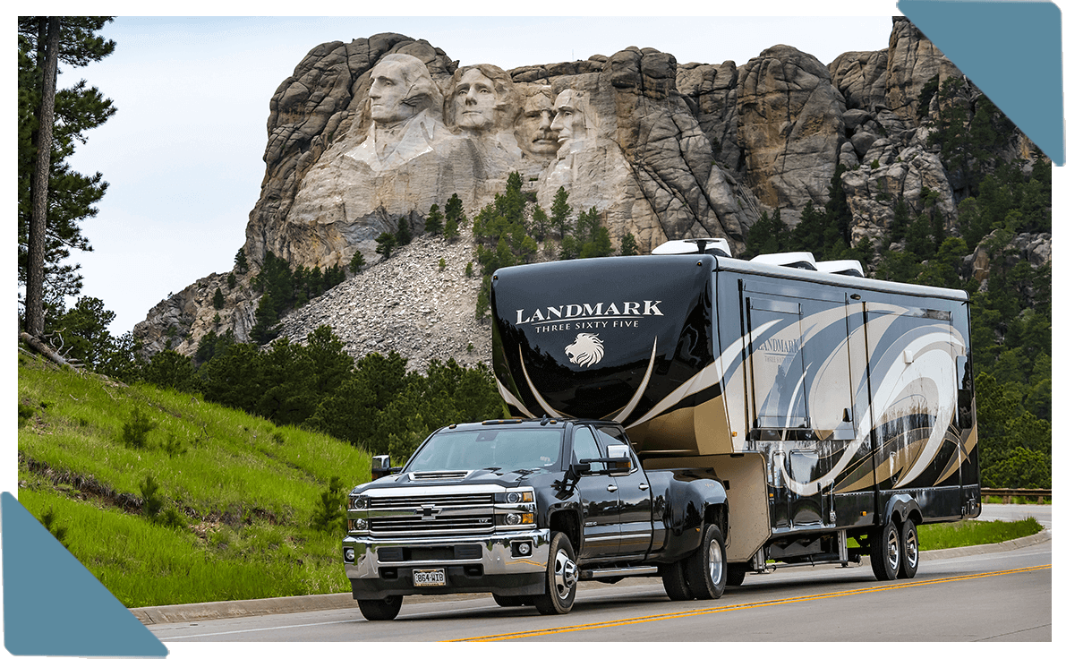 A photo of a truck hauling an RV by Mount Rushmore.